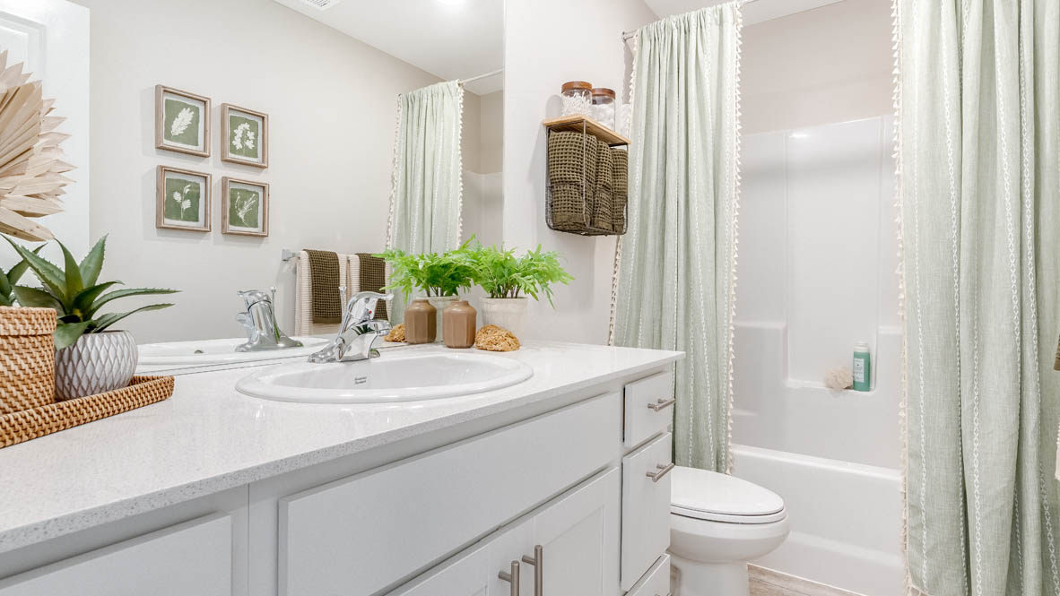 East Park Village Bathroom with white quartz countertops, mirrors, plants, toilet, and a bathtub