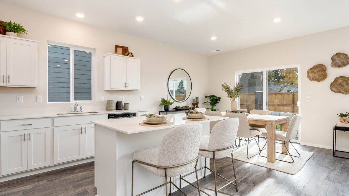 East Park Village Kitchen with island and a breakfast bar, two chairs, white cabinets, stainless steel appliances, quartz countertops, a window, decorations, and laminate flooring