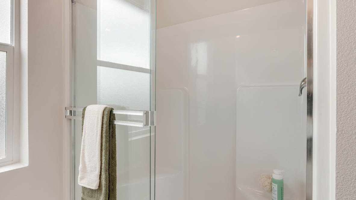 East Park Village Primary bathroom with view of walk in closet, white cabinets, quartz countertops, mirror, and window