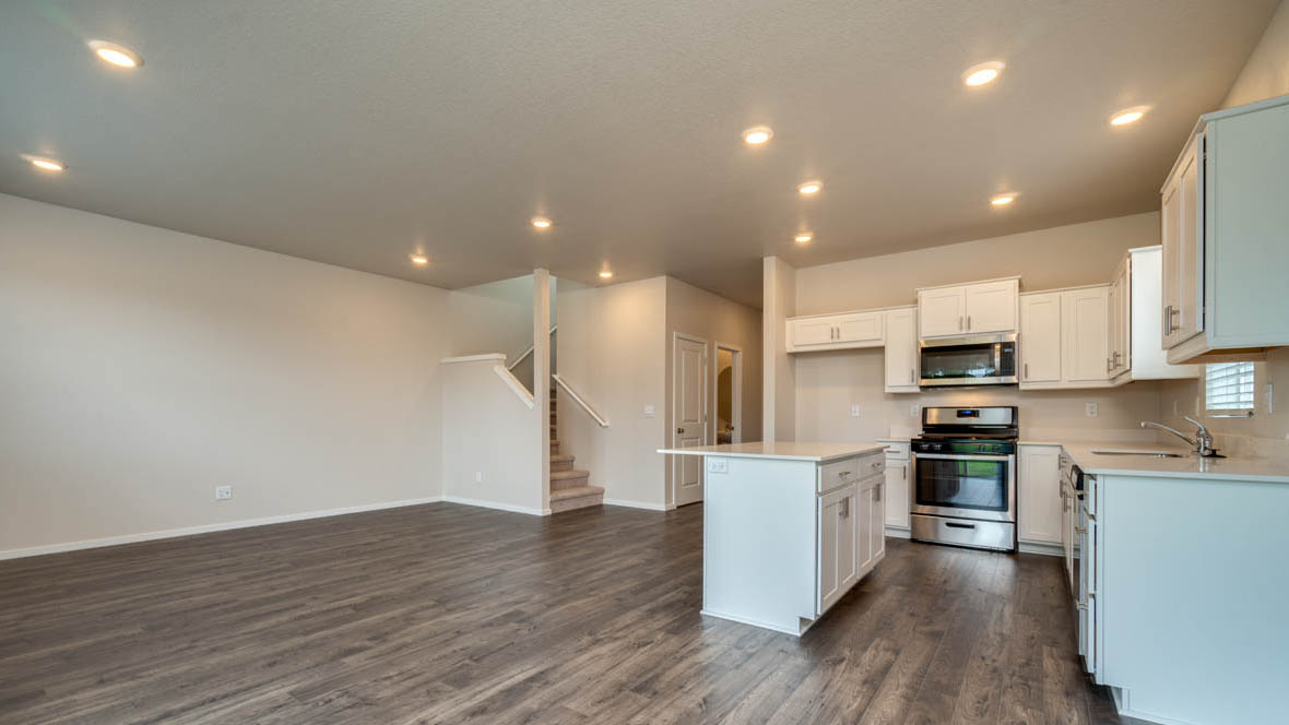 East Park Village great room with laminate flooring, white walls, and kitchen with white cabinets
