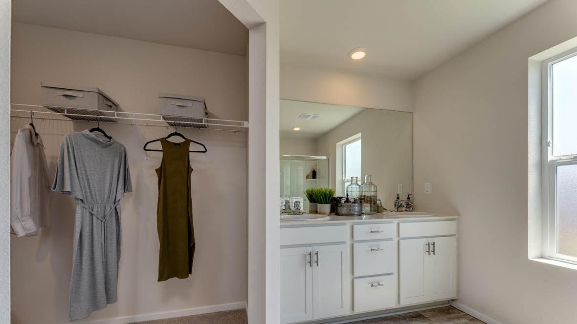 East Park Village bathroom with double sink vanity, mirror, shower, and window