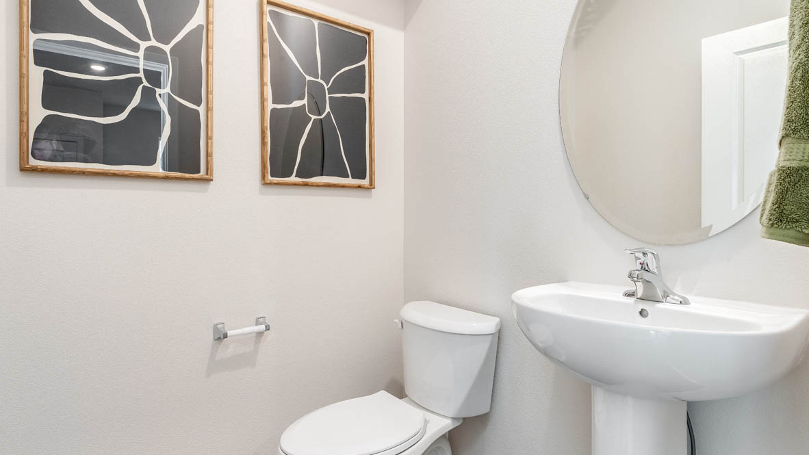 East Park Village Powder room with two paintings, a mirror, single sink vanity, and a toilet