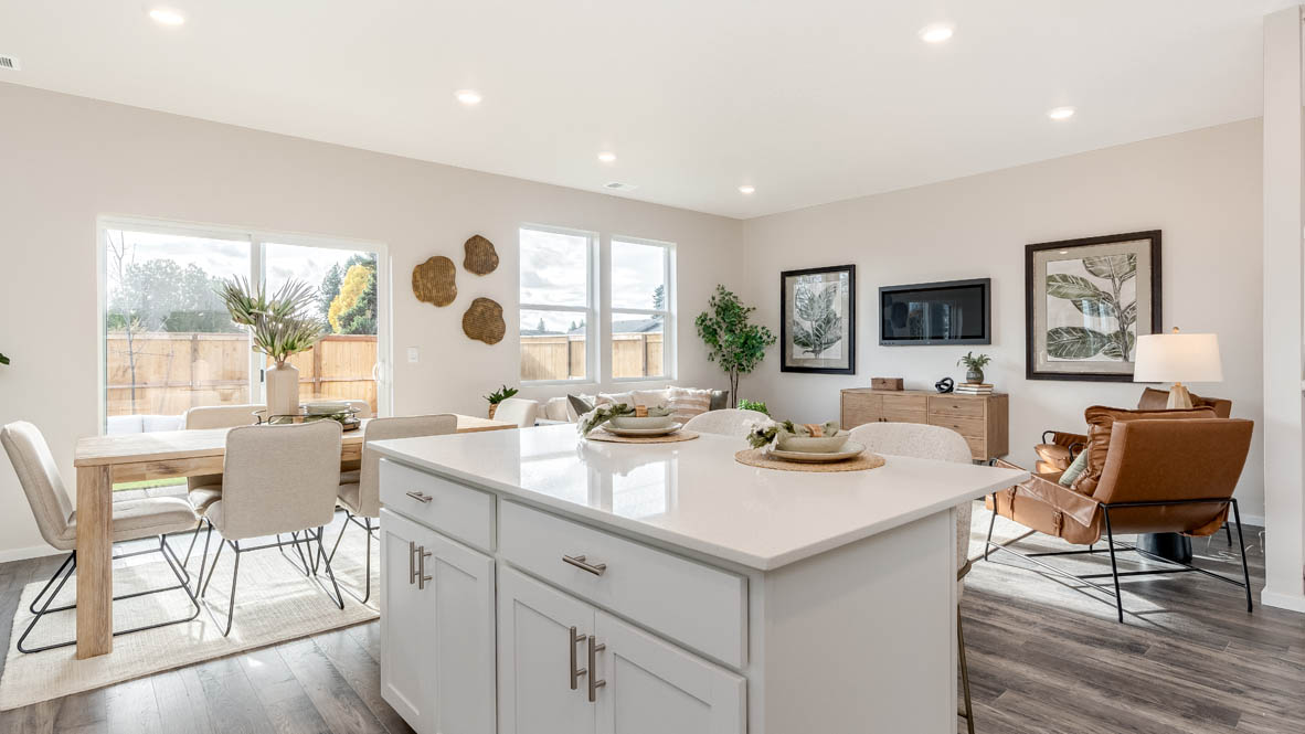 East Park Village Kitchen with white cabinets, an island with a breakfast bar, two chairs, and view of kitchen and dining room