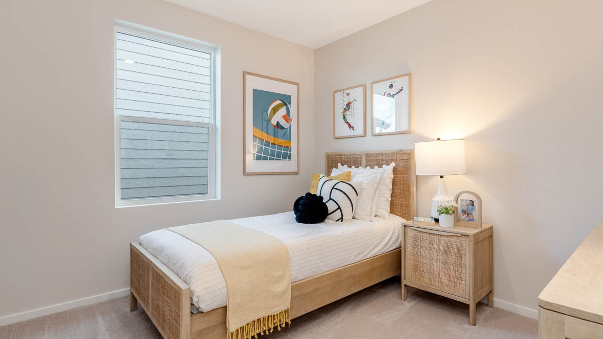 East Park Village Bedroom with a bed with sheets, light stained bed frame, end table with a lamp, paintings, and a window