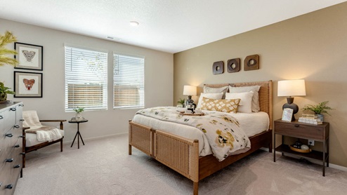 East Park Village Primary bedroom with two accent tables on either sides of the bed, art hung on the walls, king bed, and dark wood accent furniture