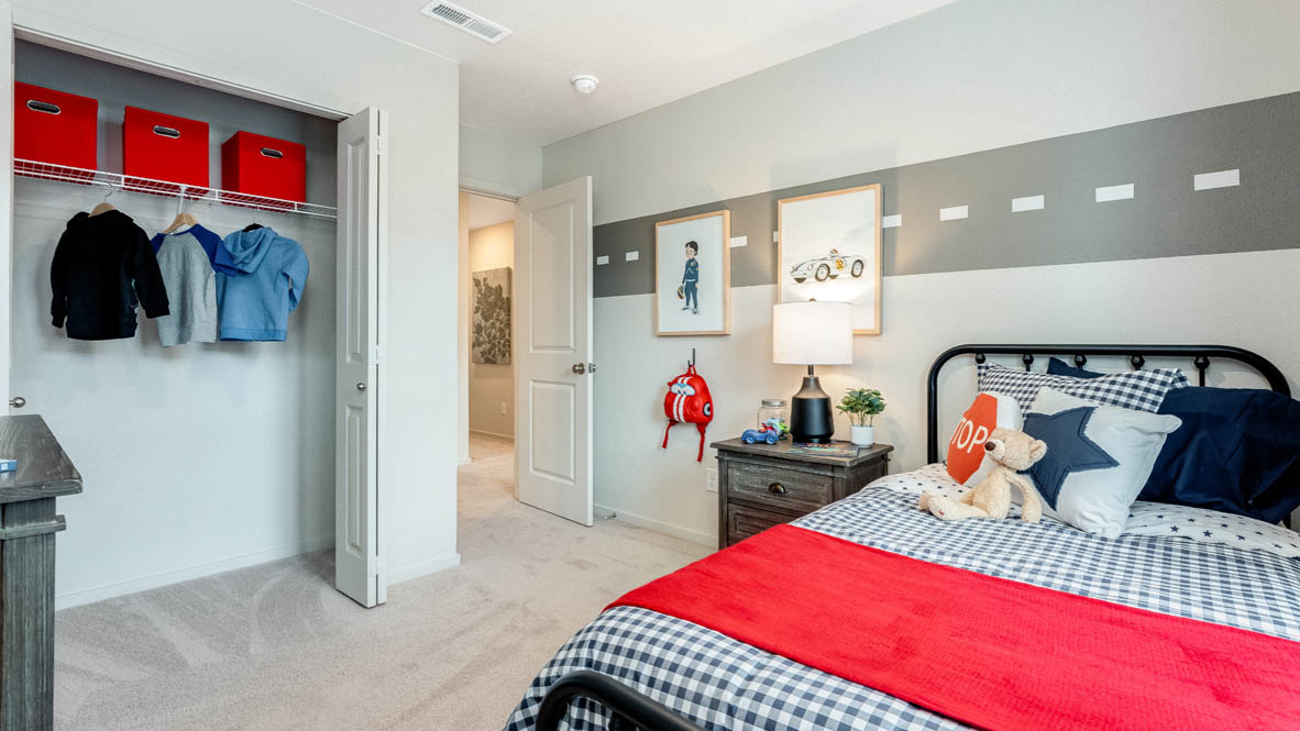 East Park Village bedroom with a dark brown dresser, circle mirror, painting, blue curtains, carpet, and closet