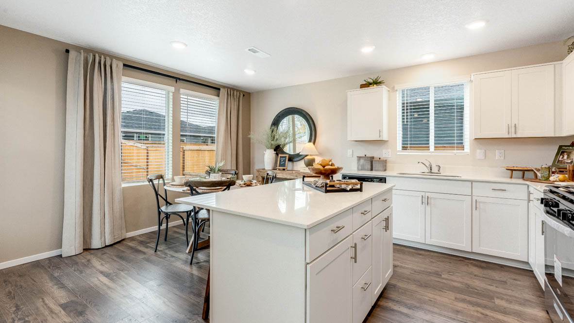 East Park Village kitchen with white quartz countertops, laminate flooring, island with a breakfast bar, shaker style cabinets, windows with blinds, kitchen window, stainless steel appliances