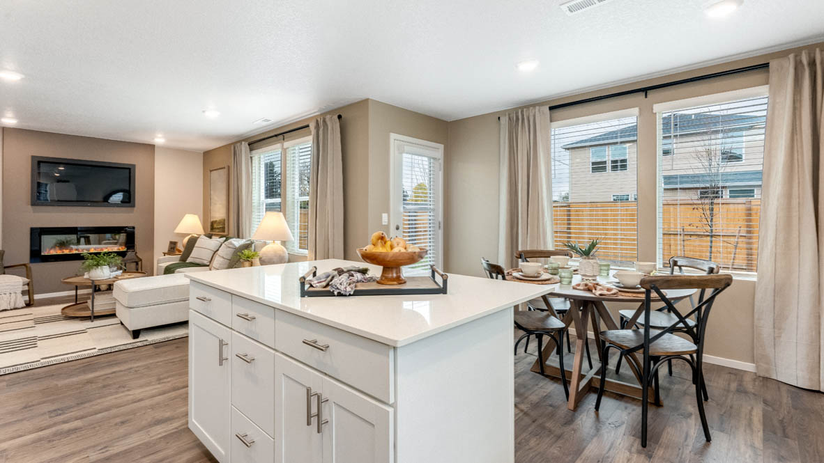 East Park Village kitchen and dining room with white quartz countertops, laminate flooring, island with a breakfast bar, shaker style cabinets, windows with blinds, kitchen window, stainless steel appliances, and view of dining room