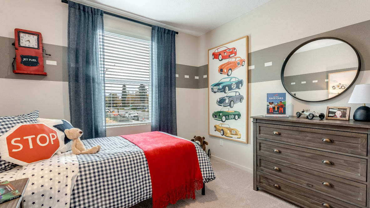 East Park Village bedroom with a dark brown dresser, circle mirror, painting, blue curtains, carpet, and bedroom