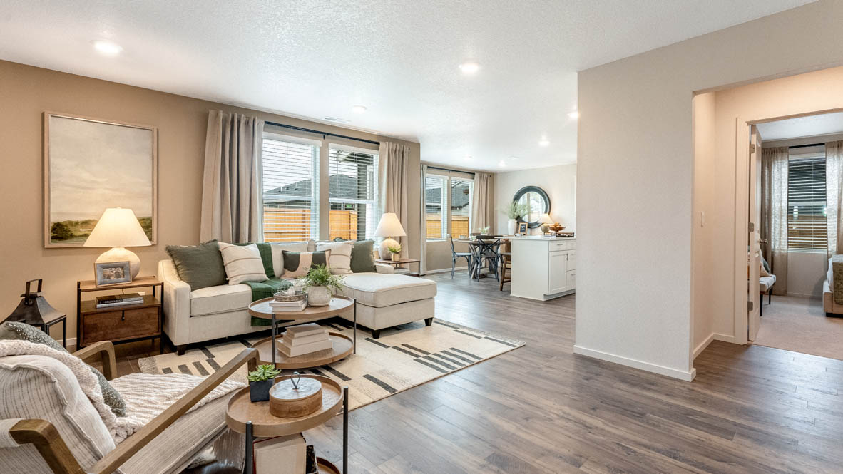 East Park Village great room with laminate flooring, coffee table, rug, rocking chair, white couch, lamp with end table, painting on tan wall, lights, and windows with blinds