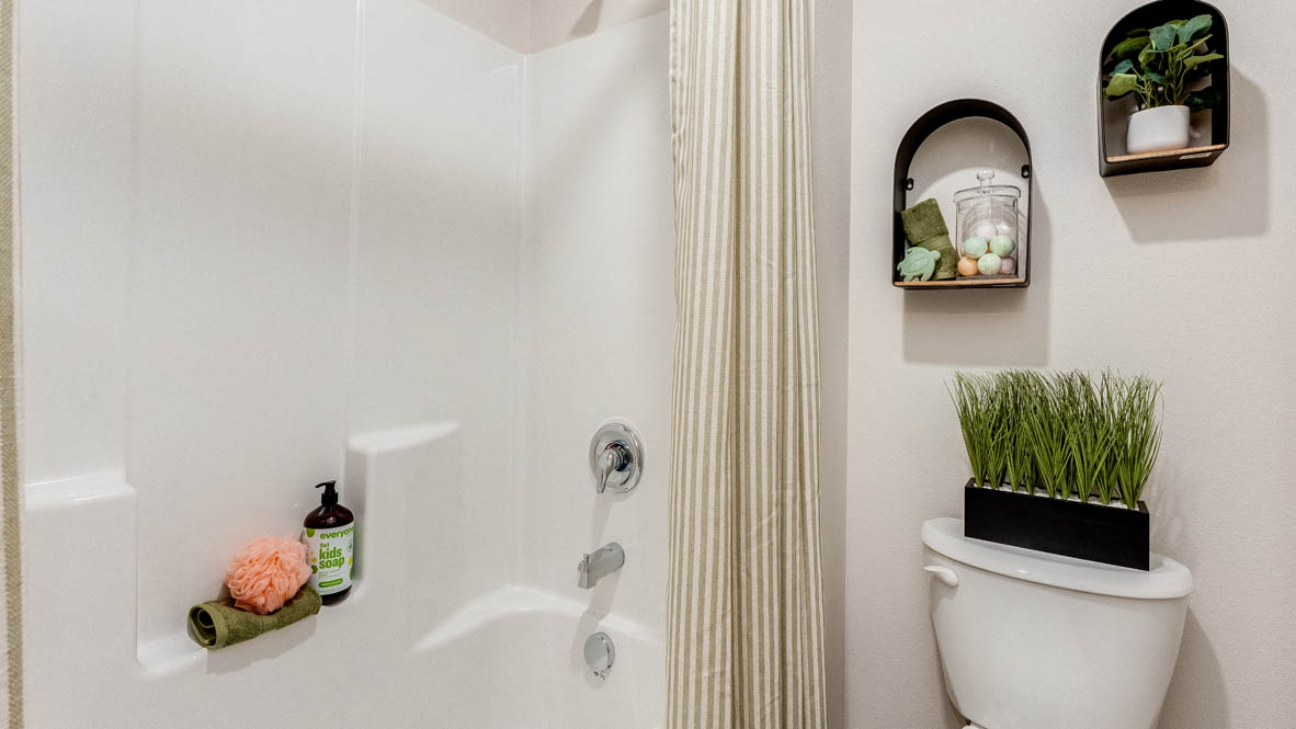 East Park Village bathroom white tub/shower, two decorations, plant