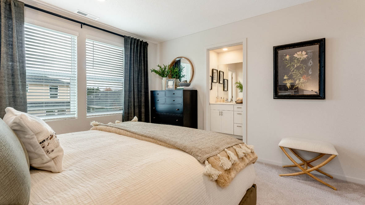 East Park Village Primary Bedroom with carpet, blue curtains, lamps with end tables, bedding, painting, with view of en suite bathroom