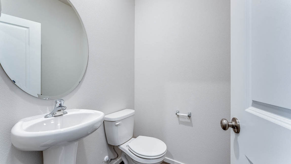 East Park Village powder room with sink, toilet, and round mirror