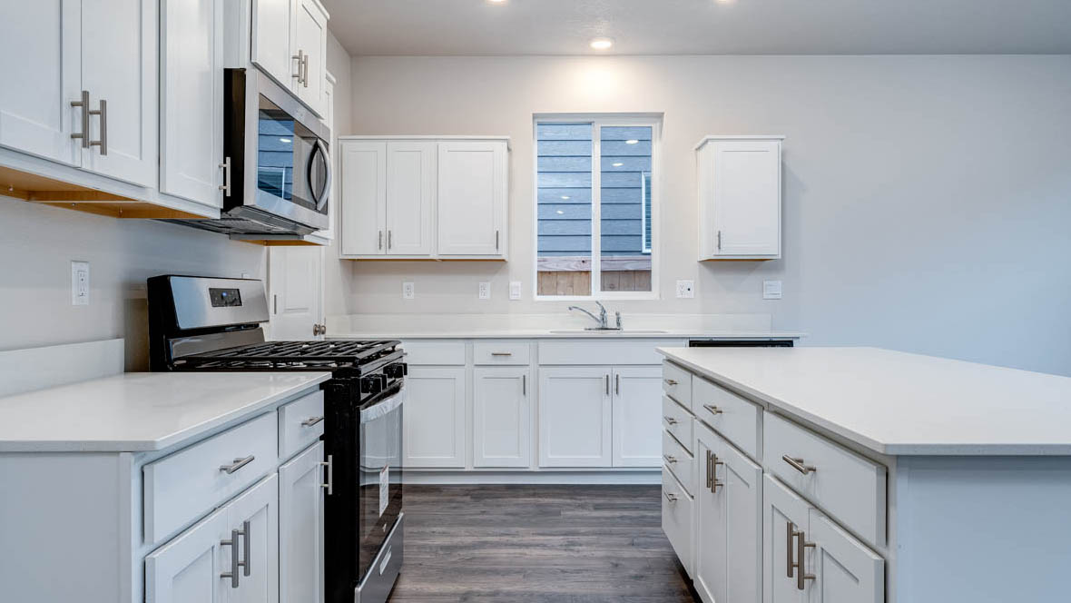 East Park Village kitchen with stainless steel appliances, island, window, cabinets, and laminate flooring