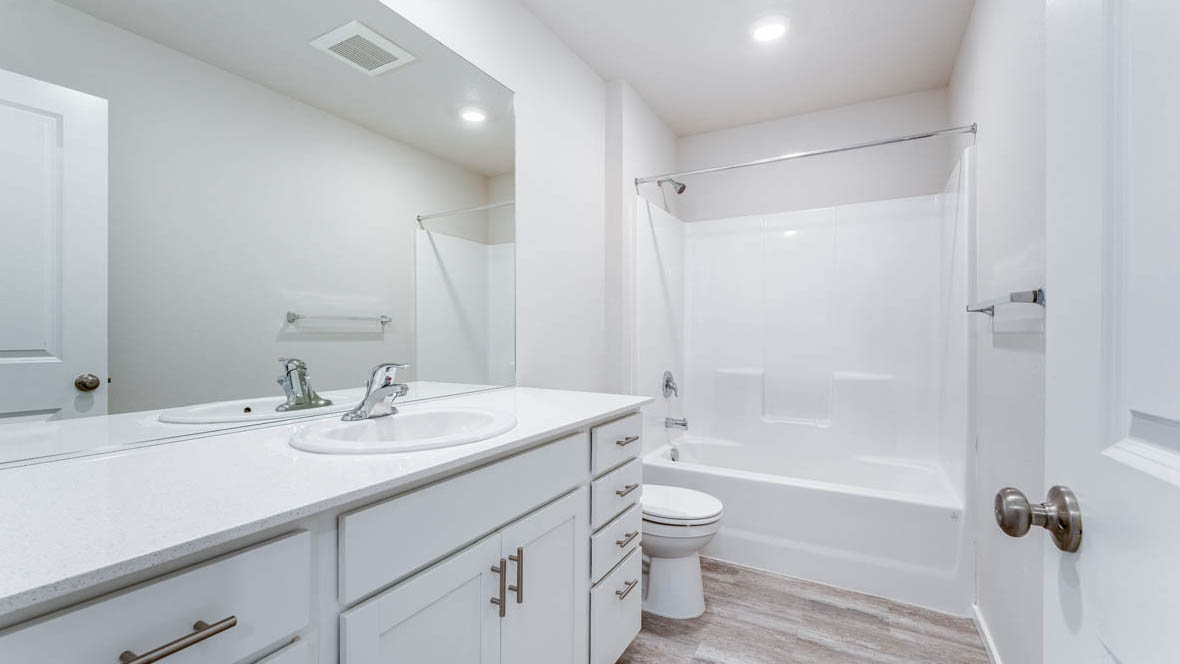 East Park Village bathroom with sink, toilet, shower tub, and mirror