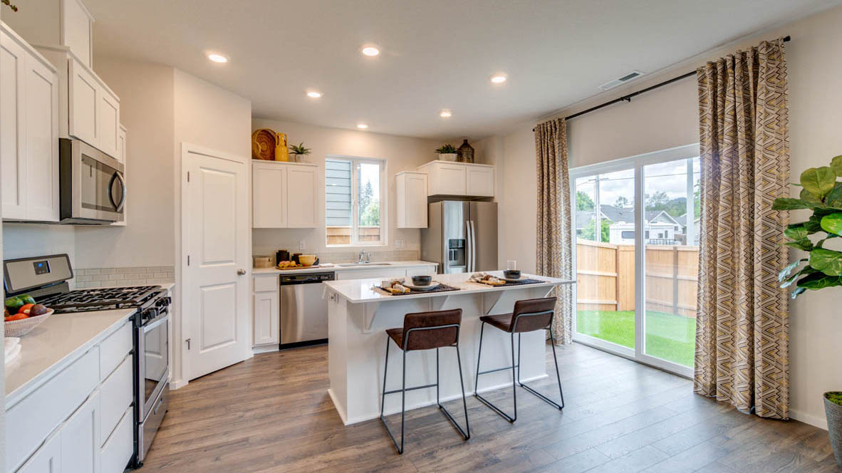 East Park Village Kitchen with white quartz countertops, white shaker cabinets, stainless steel appliances, and an island with two chairs set at it
