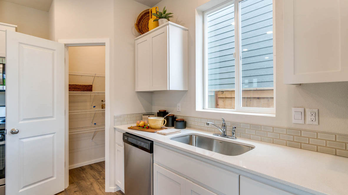 East Park Village Kitchen with white quartz countertops, white shaker cabinets, stainless steel appliances, and an island with two chairs set at it