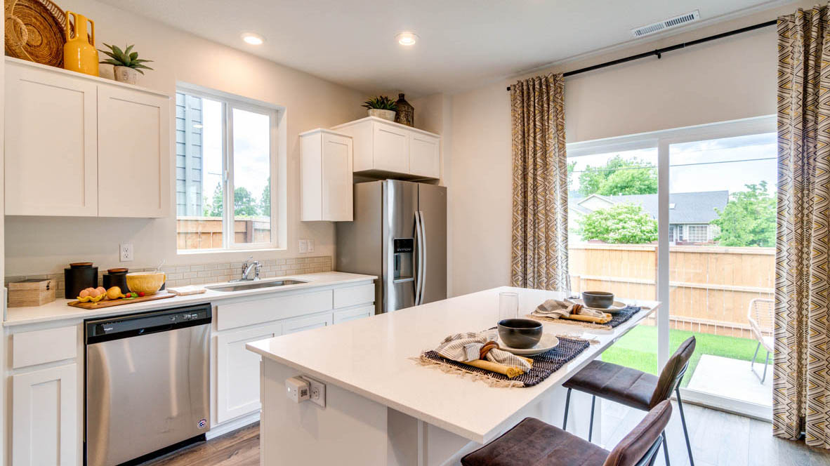 East Park Village Kitchen with white quartz countertops, white shaker cabinets, stainless steel appliances, and an island with two chairs set at it
