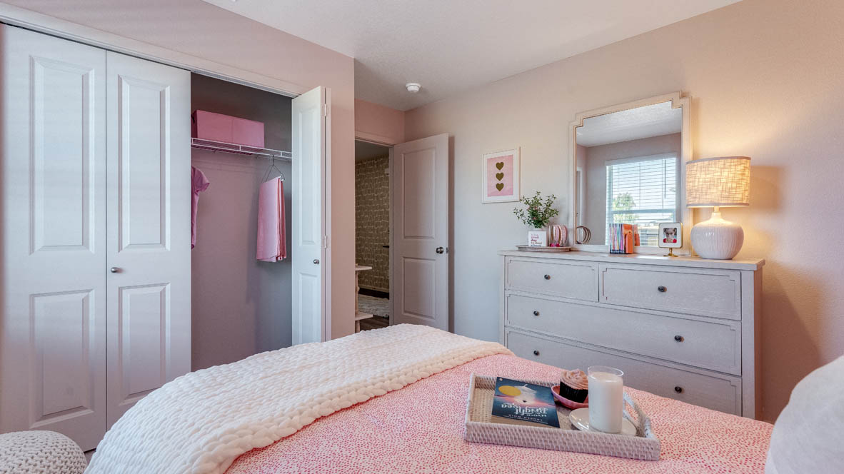 East Park Village Bedroom with bed, carpet, closet, paintings, end table with lamp, and paintings