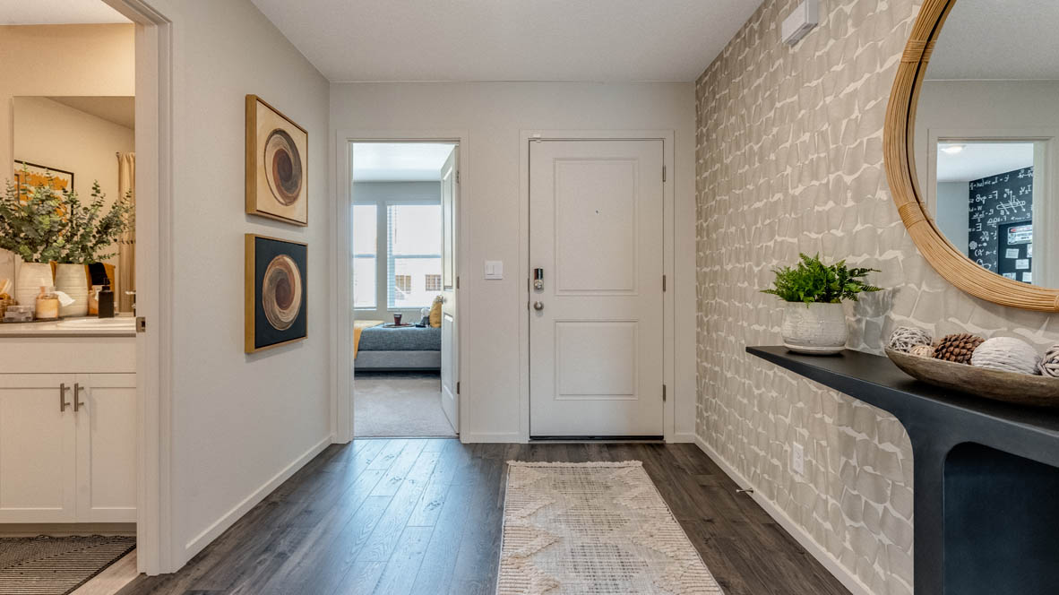 East Park Village Entry with long rug, console table with mirror, paintings, laminate flooring, with view of vedroom