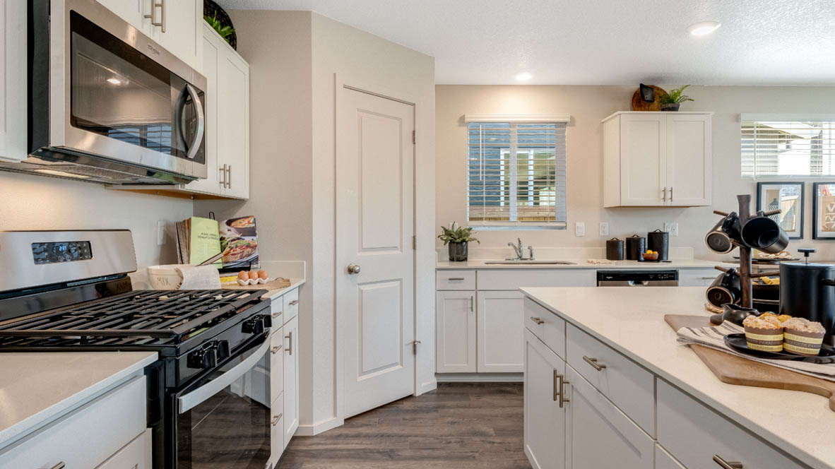 East Park Village Kitchen with quartz countertops, white cabinets, windows, pantry, and view of dining room, and great room