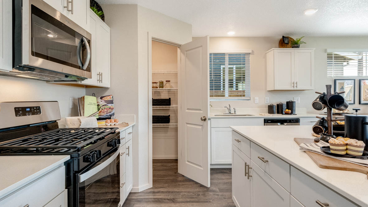 East Park Village Kitchen with quartz countertops, white cabinets, windows, pantry, and view of dining room, and great room