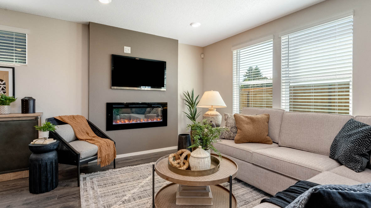East Park Village Great room with carpet, laminate flooring, windows, couch, coffee table, single chair with end piece, fireplace, tv, and decorative plants with view of dining room and kitchen