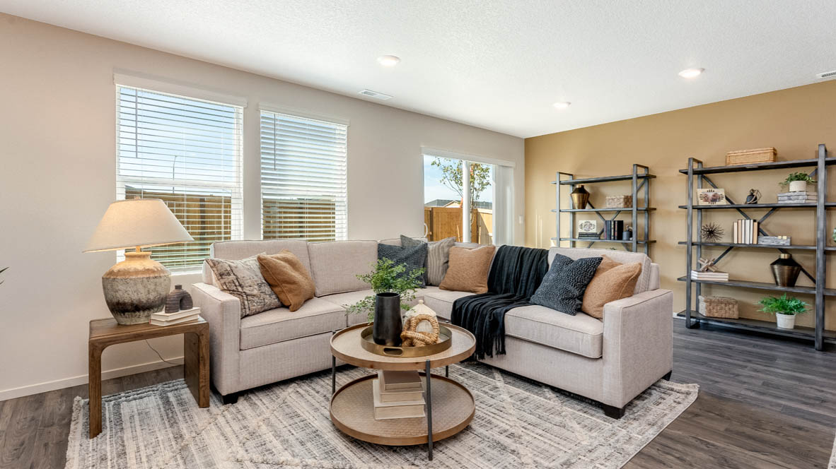 East Park Village Great room with carpet, laminate flooring, windows, couch, coffee table, single chair with end piece, fireplace, tv, and decorative plants with view of dining room and kitchen