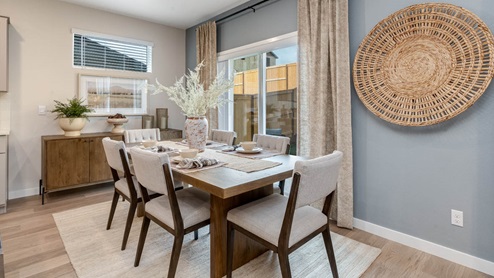 Misty Meadows dining room table with six places set over an area rug next to an accent wall with a sliding glass door