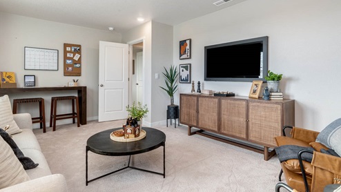 Misty Meadows bonus room with accent wall and couch facing a media console and tv