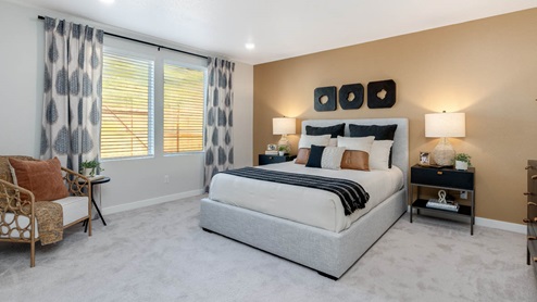 Misty Meadows primary bedroom with tan accent wall and large bed with bedside accent tables and carpeting