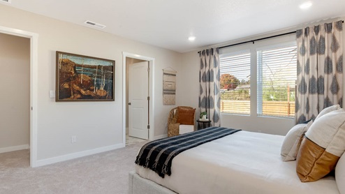 Misty Meadows primary bedroom with tan accent wall and large bed with bedside accent tables and carpeting