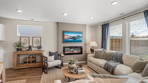 Addysen Park great room with large L shaped sectional couch, area rug, fireplace, coffee table, and chair
