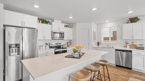 Addysen Park kitchen with island and white shaker style cabinets, white quartz countertops, laminate flooring, and staged furniture