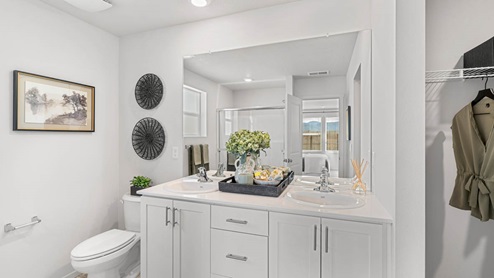 Addysen Park primary bathroom with double sink vanity and white shaker style cabinets and white solid surface countertops