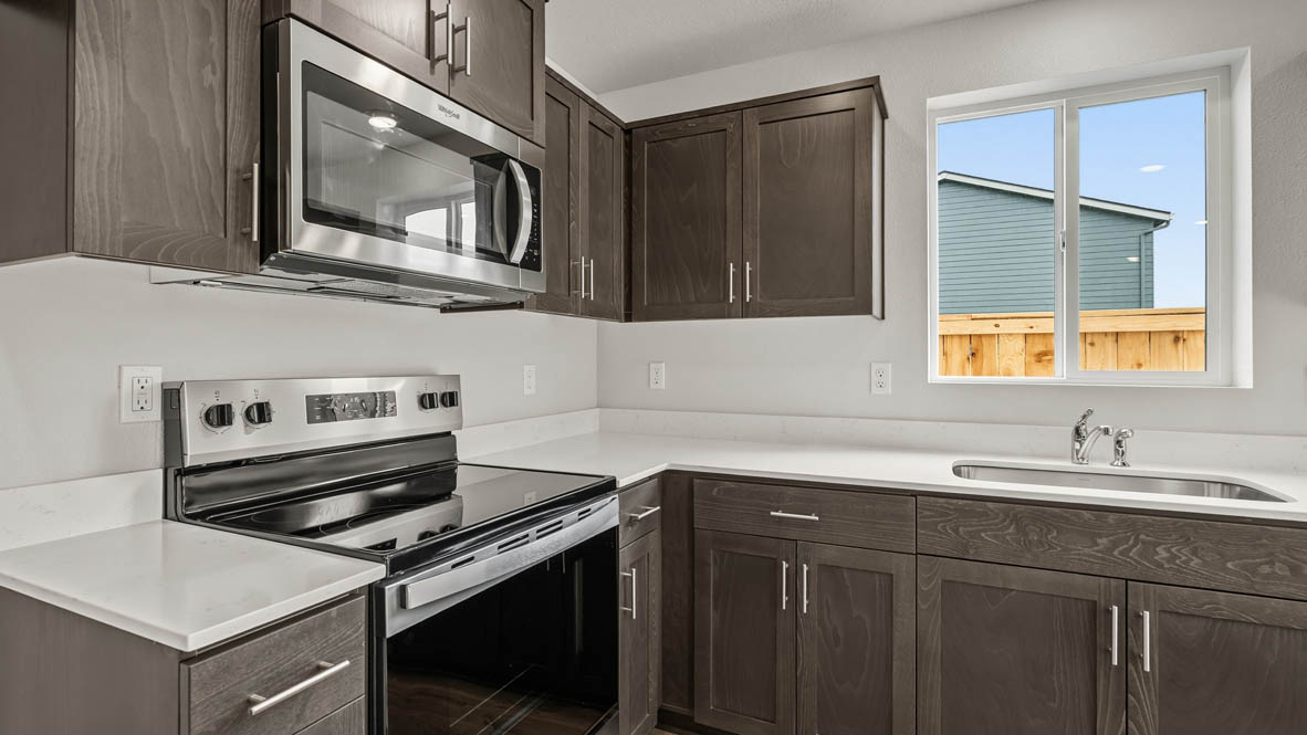 Addysen Park kitchen with dark stained cabinets, solid surface countertops, and stainless steel appliances