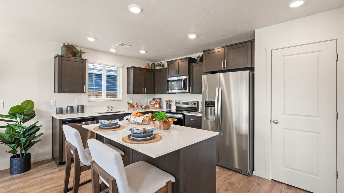Addysen Park kitchen with brown wood cabinets, a kitchen island, stainless steel appliances, and two barstool chairs