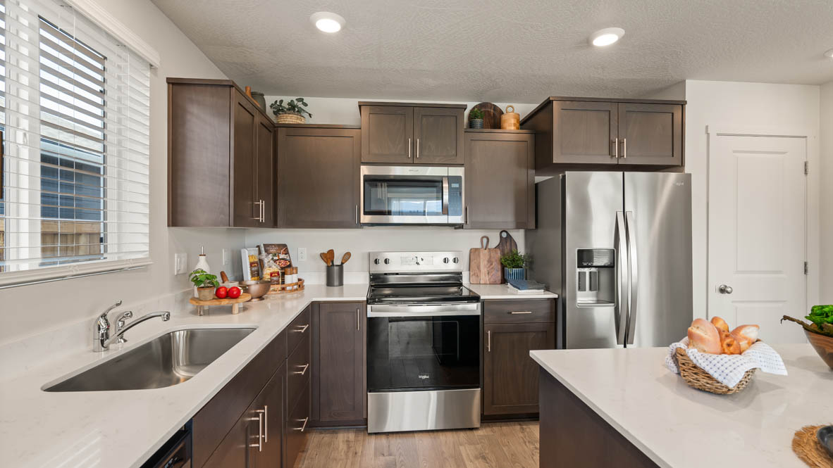 Addysen Park kitchen with brown wood cabinets, a kitchen island, stainless steel appliances, and two barstool chairs