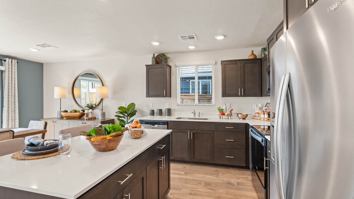 Addysen Park kitchen with brown wood cabinets, a kitchen island, stainless steel appliances, and two barstool chairs