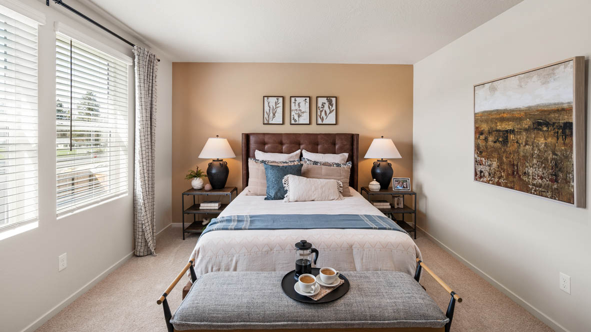 Addysen Park primary bedroom with leather headboard yellow accent wall and brown furniture