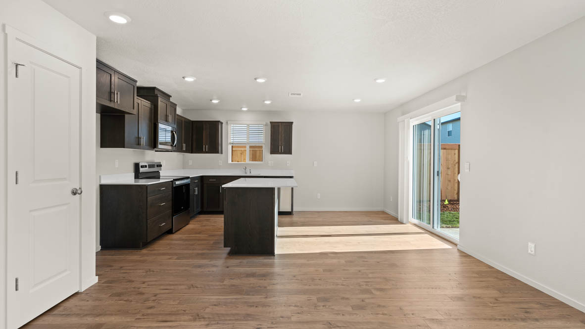 Addysen Park dining room with laminate flooring, windows, and the kitchen in the background