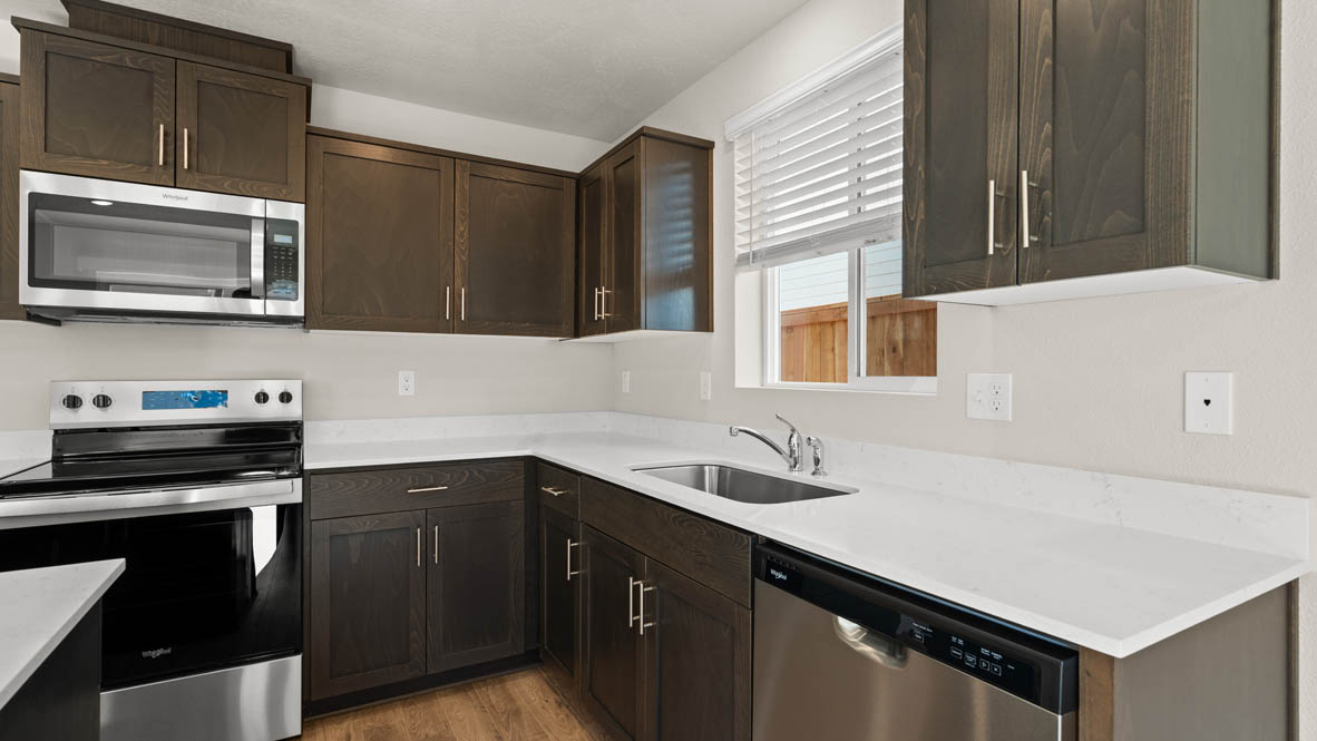 Addysen Park kitchen with laminate flooring, stainless steel appliances, cabinets, window, solid surface countertops