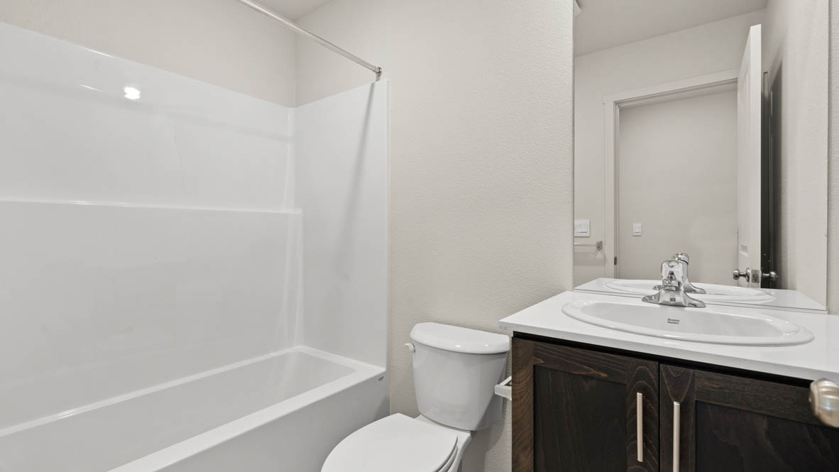 Addysen Park Downstairs bathroom with toilet, mirror, tub, and white cabinets