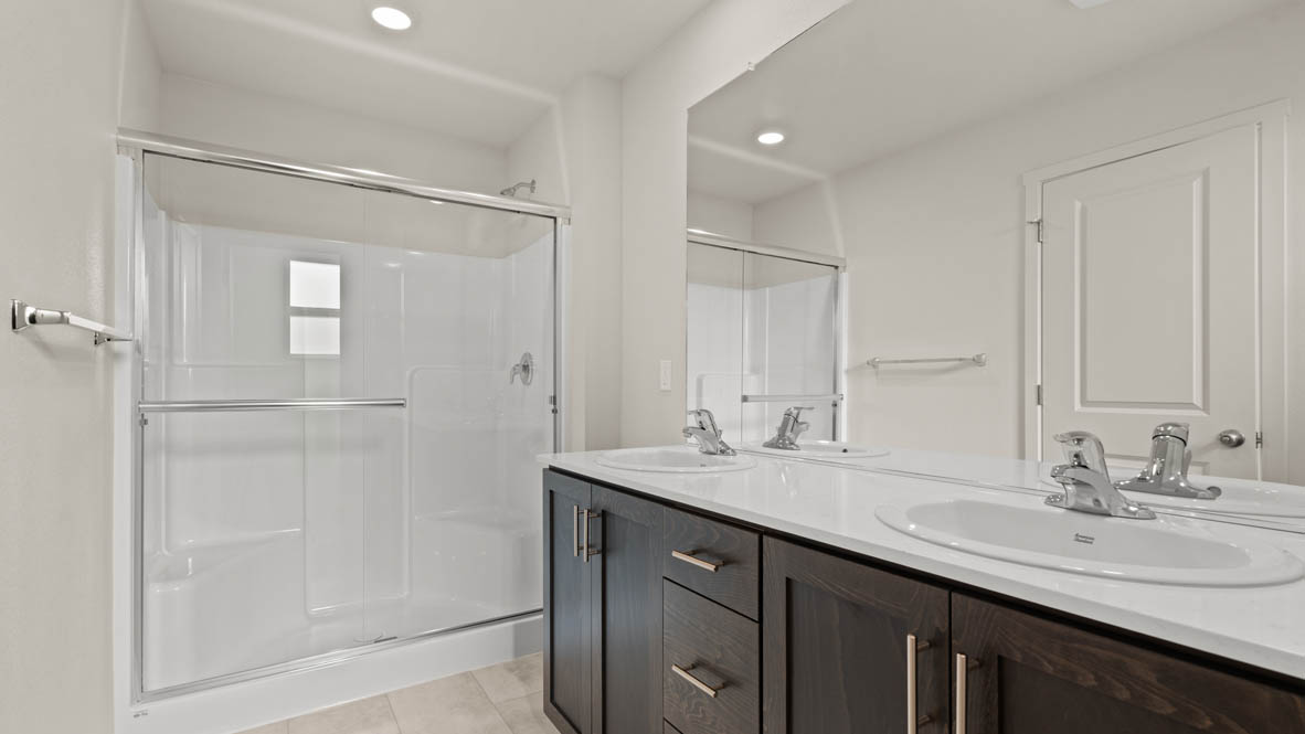 Addysen Park primary bathroom with solid surface countertops, mirror, walk in shower, and cabinets