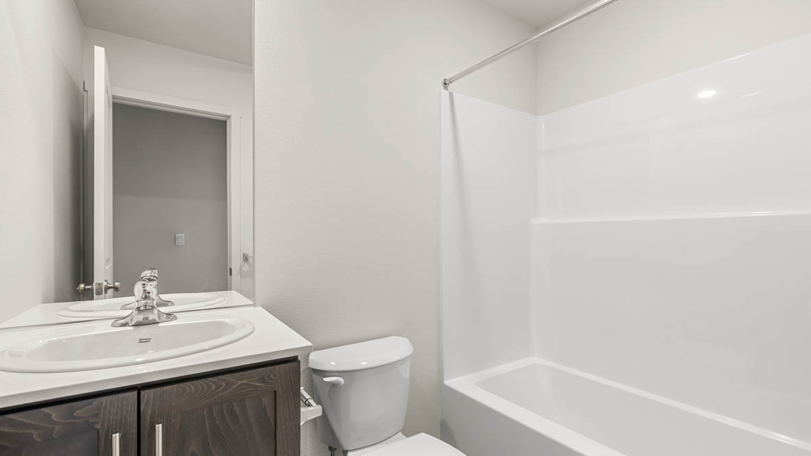 Addysen Park Downstairs bathroom with toilet, mirror, tub, and white cabinets