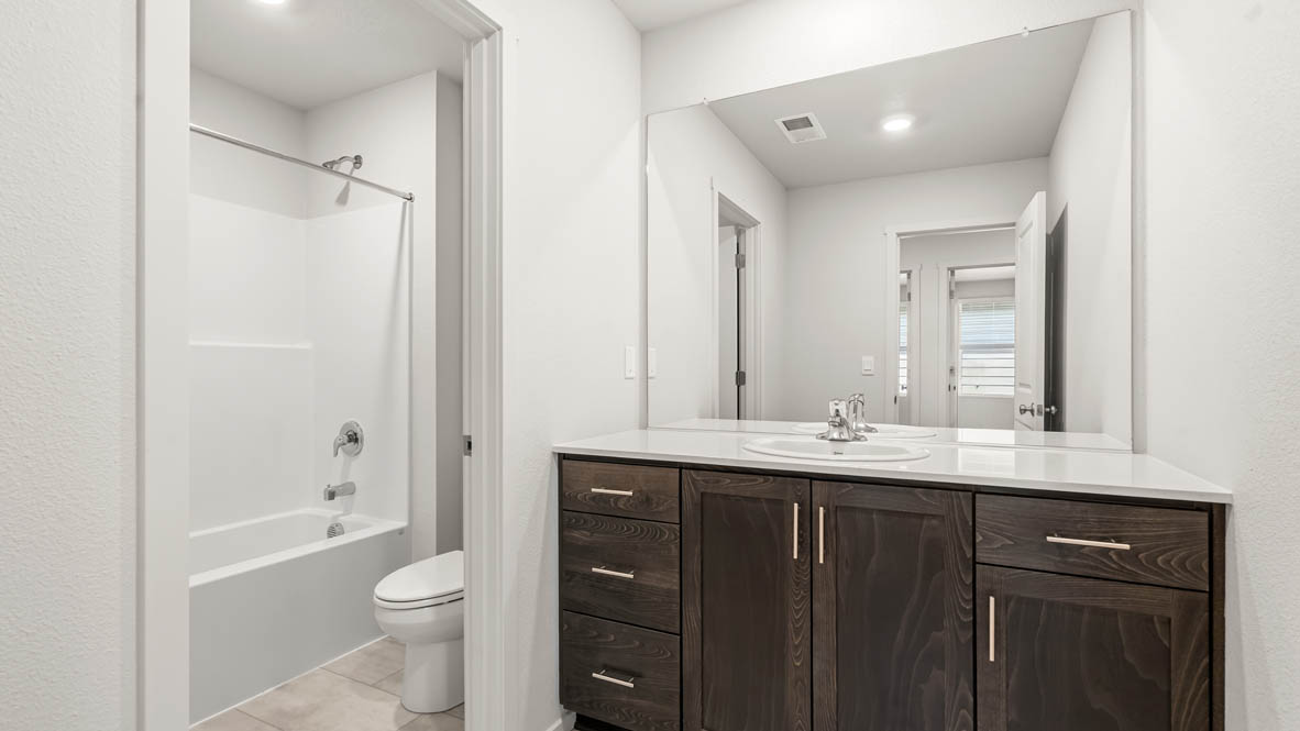 Addysen Park secondary bathroom wit quartz countertops, mirror, toilet, and shower tub