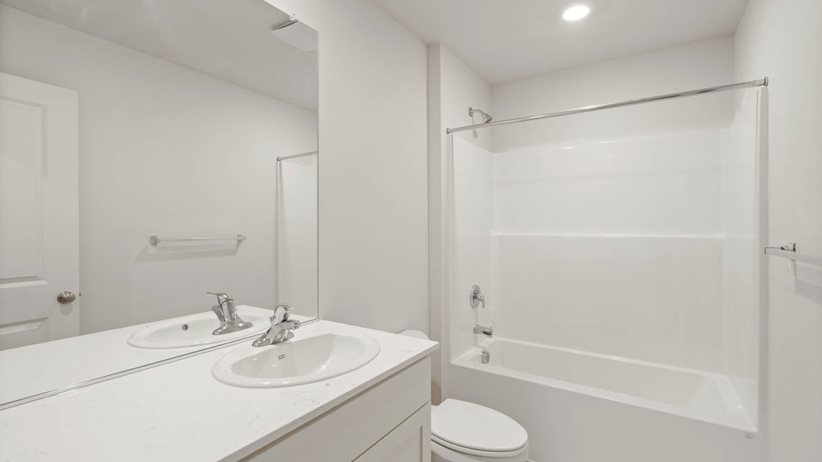Addysen Park secondary bathroom wit quartz countertops, mirror, toilet, and shower tub