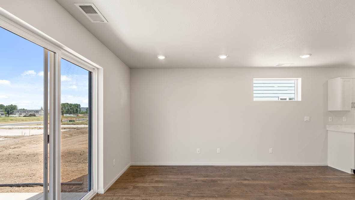 Addysen Park Great room with white walls, sliding glass door, windows, and laminate flooring