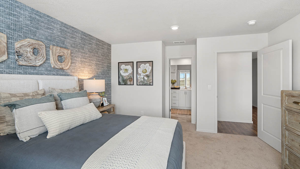 addysen park primary bedroom with blue accent wall and white walls with light wooden furniture