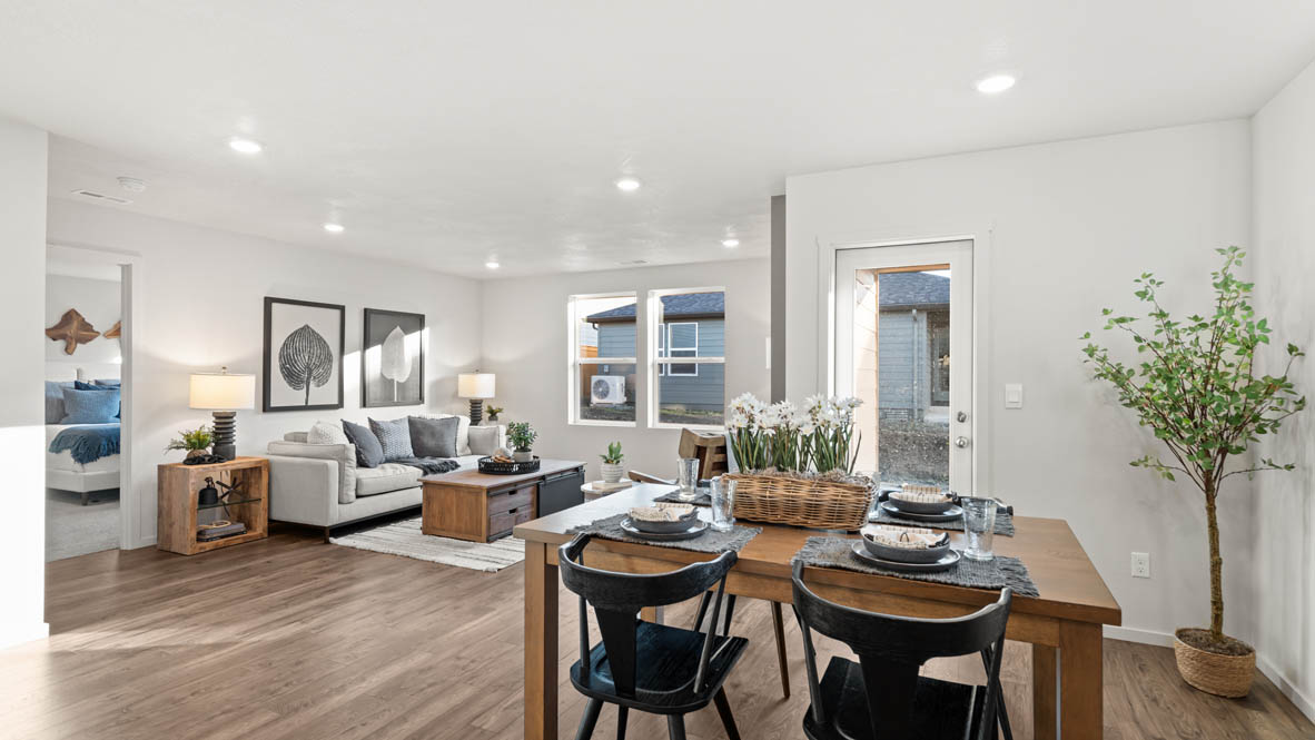 Addysen Park Dining Room with wood table and four chairs, kitchen set, tall plant, laminate flooring, door to outside, and the great roomin the background